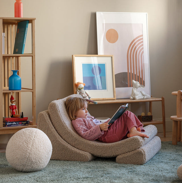 Vista lateral Sillón infantil de borreguillo Luna Beige niño leyendo habitación infantil Wigiwama Slowdeco