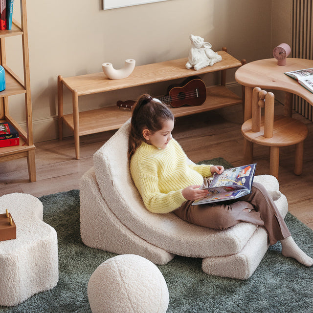 Vista lateral Sillón infantil de borreguillo Luna Blanco niña leyendo cuarto Wigiwama Slowdeco
